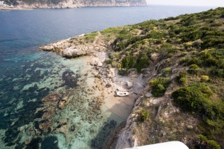 Aerial view of a lone dinghy nestling on a sandy beach of an island