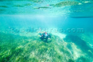 A scuba diver investigates the the seabed in the shallows