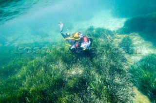 A scuba diver investigates the the seabed in the shallows