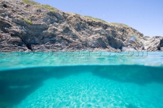 The relative calm of under water contrasts with the jagged rocky outcrop above the waterline