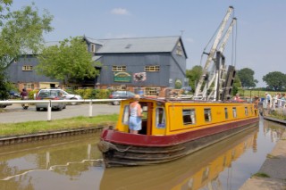 Woman on narrow boat passing through Wrenbury lift bridge on the Llangollen canal,Wrenbury,Cheshire,England.July 2006.