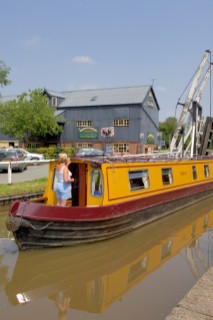 Woman on narrow boat passing through Wrenbury lift bridge on the Llangollen canal,Wrenbury,Cheshire,England.July 2006.