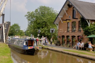 People on narrow boat passing through Wrenbury lift bridge outside the Dusty Miller pub on the Llangollen canal,Wrenbury,Cheshire,England.July 2006.