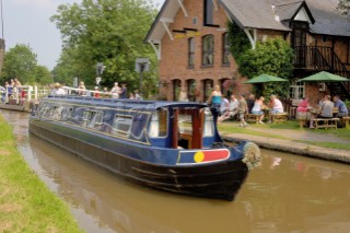 People on narrow boat passing through Wrenbury lift bridge outside the Dusty Miller pub on the Llangollen canal,Wrenbury,Cheshire,England.July 2006.