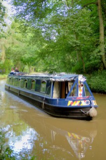 Man and woman on narrow boat approaching Ellesmere tunnel,Llangollen canal,Ellesmere,Shropshire,England.July 2006.