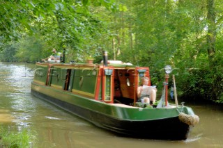 Man and woman on narrow boat approaching Ellesmere tunnel,Llangollen canal,Ellesmere,Shropshire,England.July 2006.