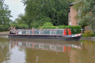 People on narrow boat passing house  on the Llangollen canal at Ellesmere,Shropshire,England.