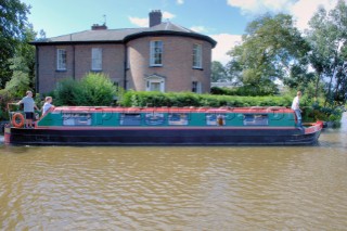 People on narrow boat passing house  on the Llangollen canal at Ellesmere,Shropshire,England.