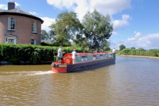 People on narrow boat passing house  on the Llangollen canal at Ellesmere,Shropshire,England.