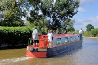 People on narrow boat passing house  on the Llangollen canal at Ellesmere,Shropshire,England.