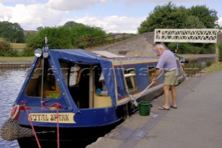 Man washing down narrow boat on the Llangollen canal at Ellesmere,Shropshire,UK.July 2006.