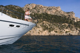 A couple admire the view from the deck of a power boat beneath a clear blue sky