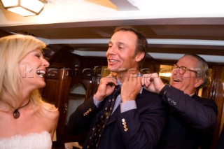 VALENCIA, SPAIN - May 14th: Onboard the classic yacht Tuiga, Bruno Trouble of Louis Vuitton (right) presents a neck tie to Ernesto Bertarelli owner of the Alinghi syndicate (centre), whilst his wife Kirsten looks on, at the exclusive Tuiga Party during the Louis Vuitton Cup Semi Finals.