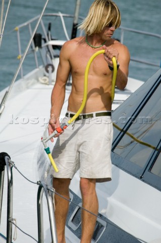 Young man spraying the deck with hose and water