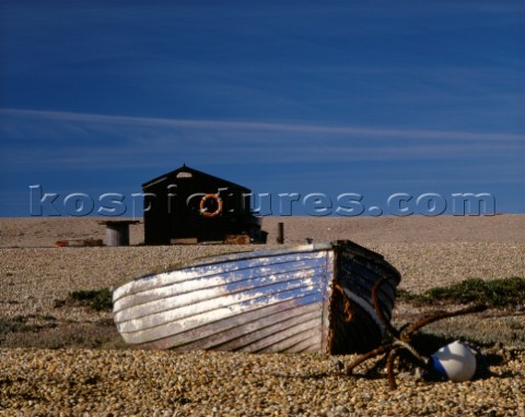 This old boat with peeling and fading paint is on the pebbles of Chesil Beach in Dorset Behind a Bla