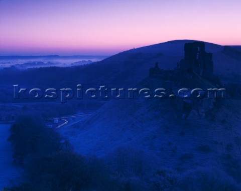 A harsh frost before dawn at Corfe in Dorset with mist on the plain near Poole Harbour The Castle ru