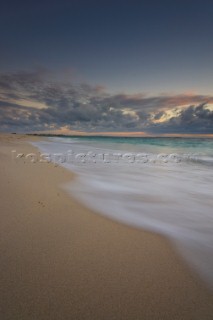 Moody sky over a sandy beach at dusk.