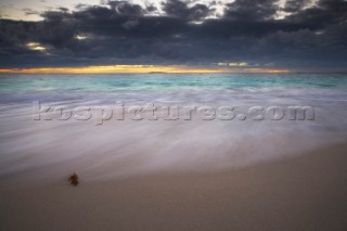 Moody sky over a sandy beach at dusk.