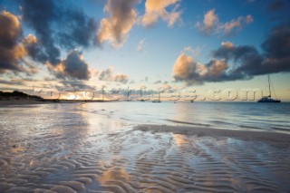 Colourful sunset over a sandy beach at low tide.