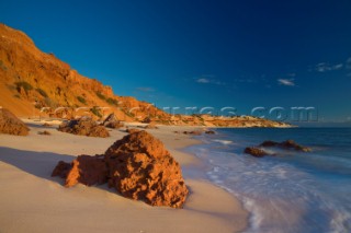 Large red cliffs meet an unspoilt beach