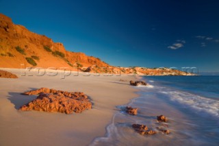 Large red cliffs meet an unspoilt beach