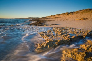 Evening light on the beach at low tide, with waves breaking in the distance