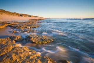 Evening light on the beach at low tide, with waves breaking in the distance