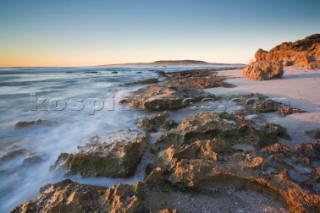 Evening light on the beach at low tide, with waves breaking in the distance