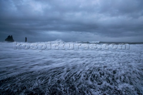 An angry stromy sea crashes against the volcanic shore near Vik Iceland