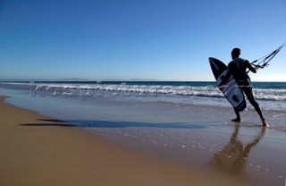 Kite surfer walking on a sandy beach in Tarifa, Spain, near Gibraltar.