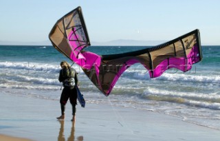 Kite surfer walking on a sandy beach in Tarifa, Spain, near Gibraltar.