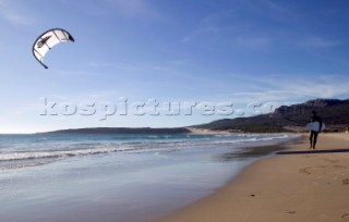 Kite surfer walking on a sandy beach in Tarifa, Spain, near Gibraltar.