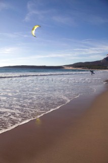 Kite surfer walking on a sandy beach in Tarifa, Spain, near Gibraltar.