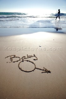 Funny amusing twist on Baby boy congratulations sign writing message on a sandy beach in Tarifa, Spain, near Gibraltar.