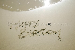 Happy Birthday sign writing message on a sandy beach in Tarifa, Spain, near Gibraltar.