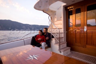 Lifestyle couple onboard a Vicem 72 classic motor yacht in the sunset Model Released.