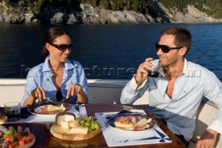 Lifestyle couple dining and eating dinner or lunch onboard a Vicem 72 classic motor yacht Model Released.