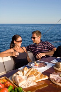 Lifestyle couple dining and eating dinner or lunch onboard a Vicem 72 classic motor yacht Model Released.