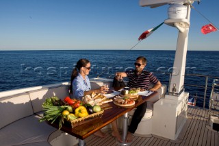 Lifestyle couple dining and eating dinner or lunch onboard a Vicem 72 classic motor yacht Model Released.