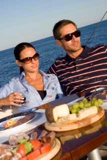 Lifestyle couple dining and eating dinner or lunch onboard a Vicem 72 classic motor yacht Model Released.