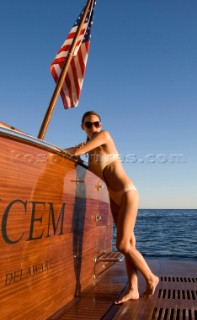 Lifestyle female onboard a Vicem 72 classic motor yacht in swimsuit on swim platform about to take a swim Model Released.