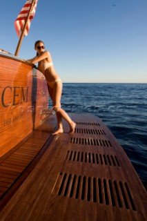 Lifestyle female onboard a Vicem 72 classic motor yacht in swimsuit on swim platform about to take a swim Model Released.