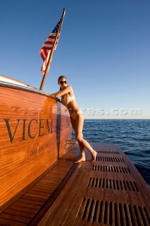 Lifestyle female onboard a Vicem 72 classic motor yacht in swimsuit on swim platform about to take a swim Model Released.