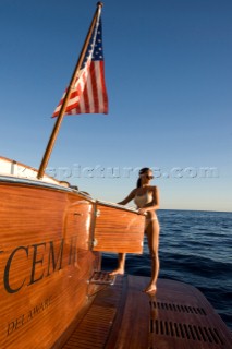 Lifestyle female onboard a Vicem 72 classic motor yacht in swimsuit on swim platform about to take a swim Model Released.