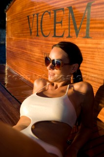 Lifestyle female onboard a Vicem 72 classic motor yacht in swimsuit on swim platform about to take a swim Model Released.