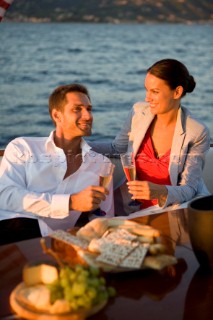 Lifestyle couple having drinks and coctails onboard a Vicem 72 classic motor yacht in the sunset Model Released.