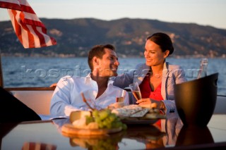 Lifestyle couple having drinks and coctails onboard a Vicem 72 classic motor yacht in the sunset Model Released.