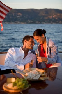 Lifestyle couple having drinks and coctails onboard a Vicem 72 classic motor yacht in the sunset Model Released.