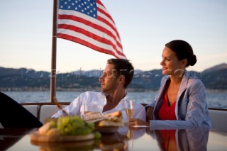 Lifestyle couple having drinks and coctails onboard a Vicem 72 classic motor yacht in the sunset Model Released.