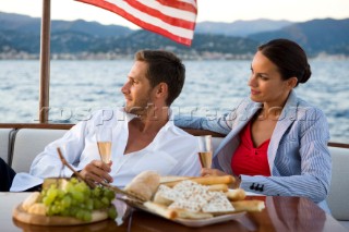 Lifestyle couple having drinks and coctails onboard a Vicem 72 classic motor yacht in the sunset Model Released.